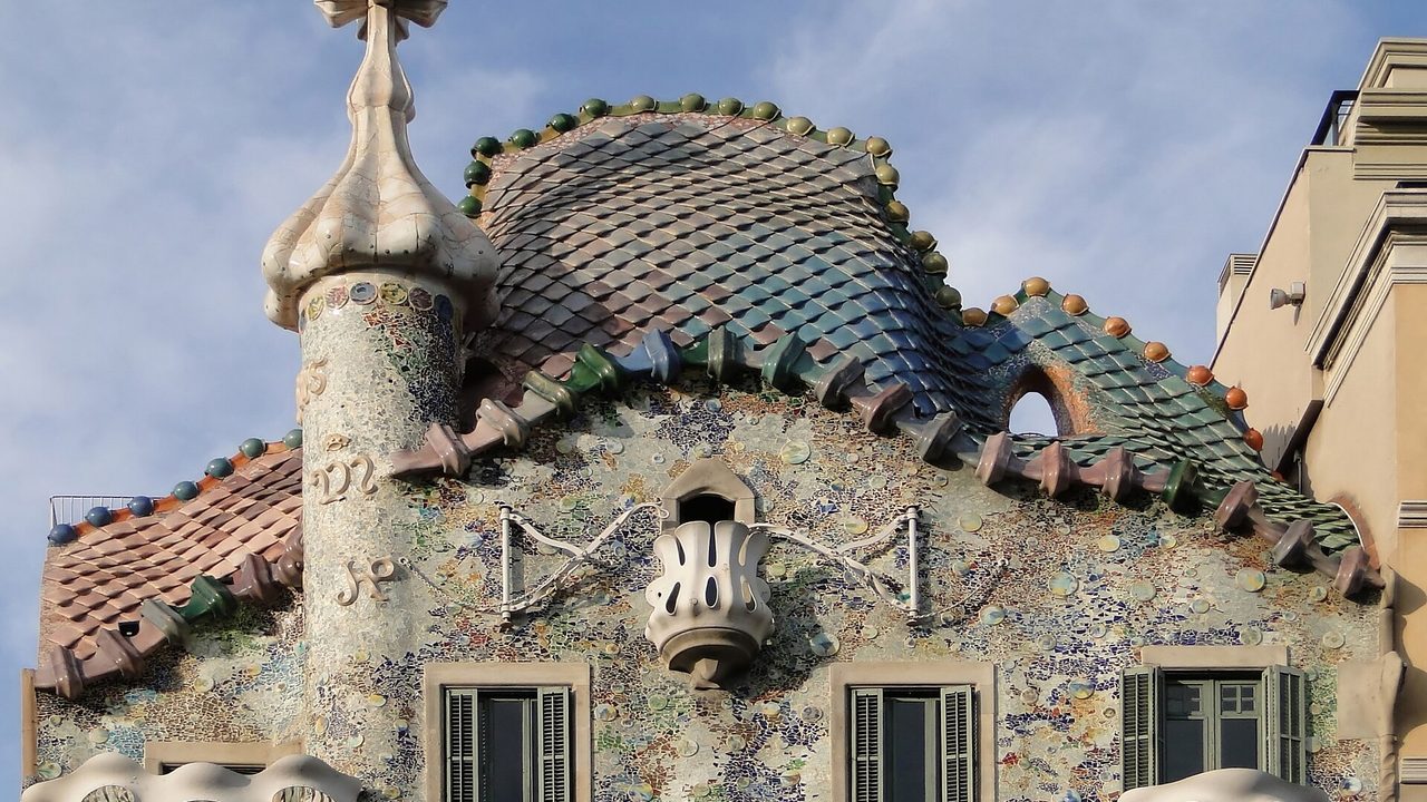 Das geschuppte, drachenartige Dach und der Turm der Casa Batlló in Barcelona vor blauem Himmel