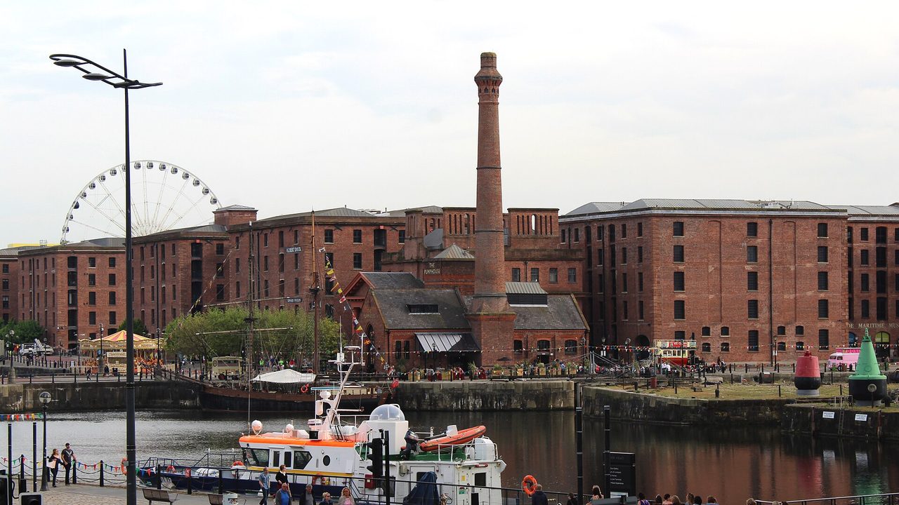 Der Royal Albert Dock und das Pump House in Liverpool an einem hellen Tag, dahinter das Riesenrad