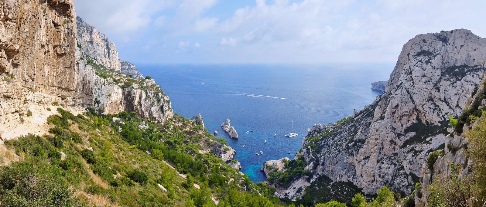 Panoramablick über die weißen Kalksteinfelsen und das türkisfarbene Wasser der Calanque de Sugiton bei Marseille