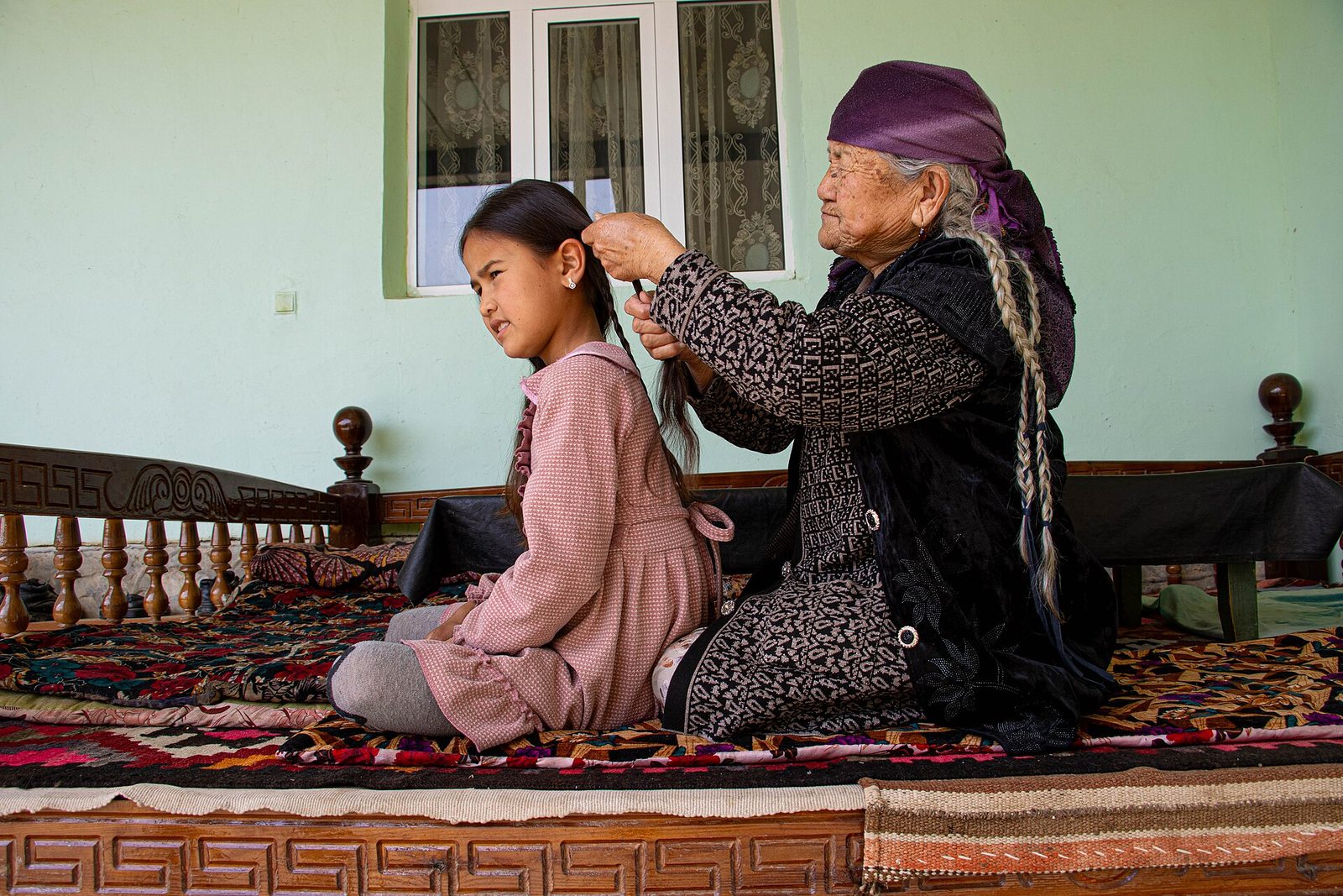 A grandmother braiding her granddaughter’s hair