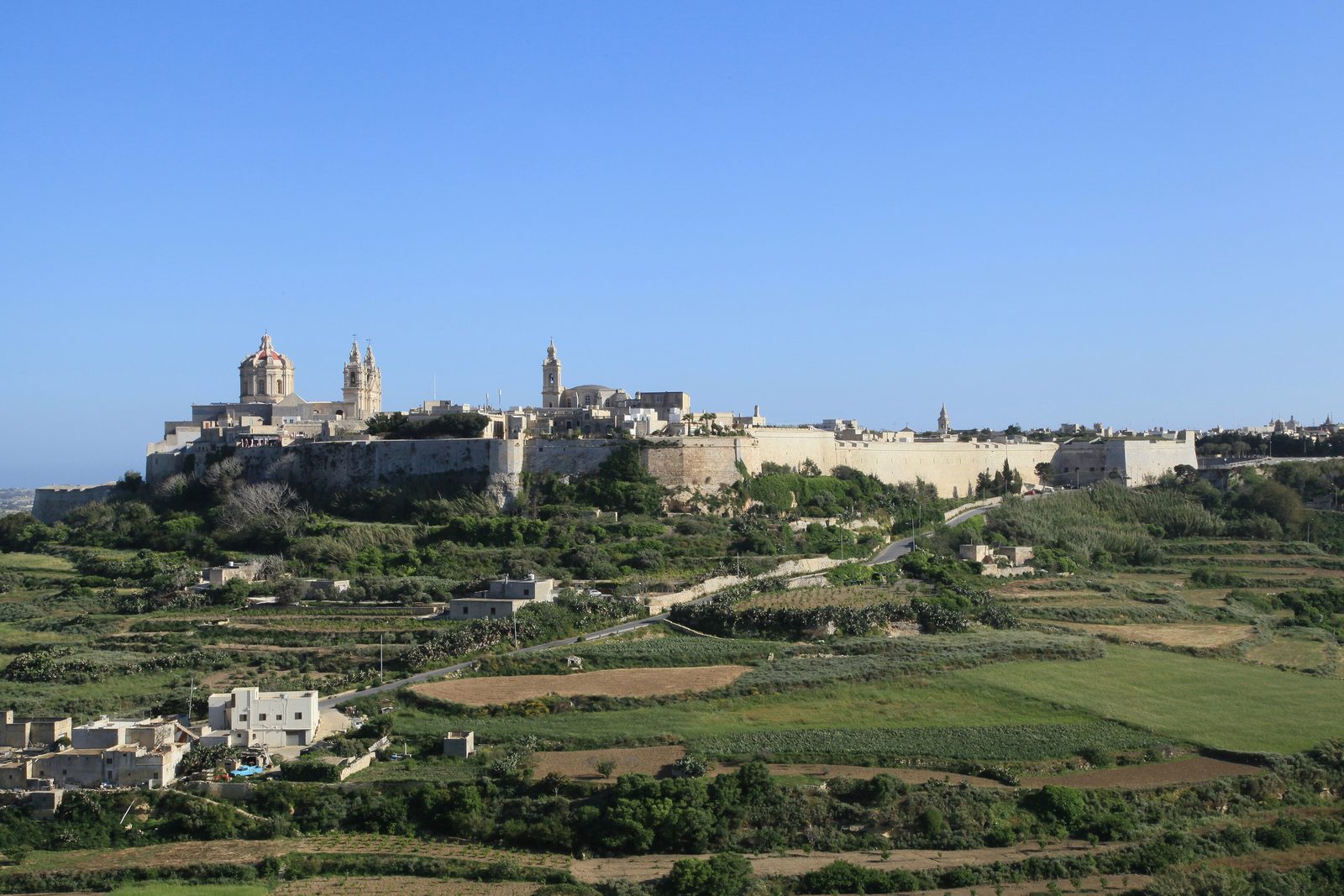 A narrow honey-coloured stone street inside the walled city of Mdina, Malta, in daylight