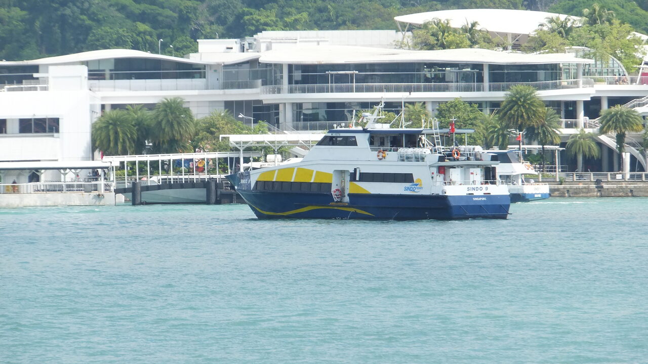 Un catamarán de Sindo Ferry amarrado frente al edificio blanco del Singapore Cruise Centre