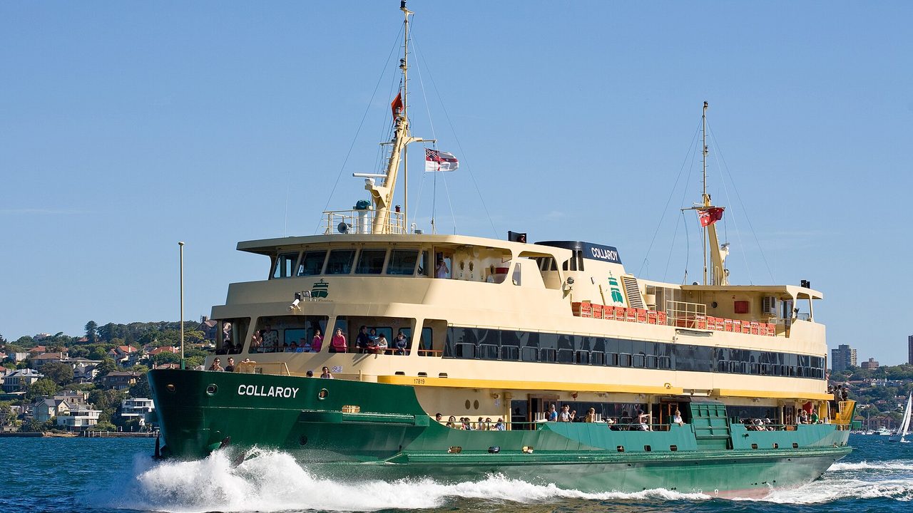 The green and cream Manly ferry Collaroy crossing Sydney Harbour under a clear blue sky